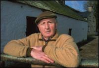 Dick Power at gate with farm building in background