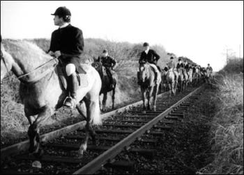 Mounted hunters on railway tracks